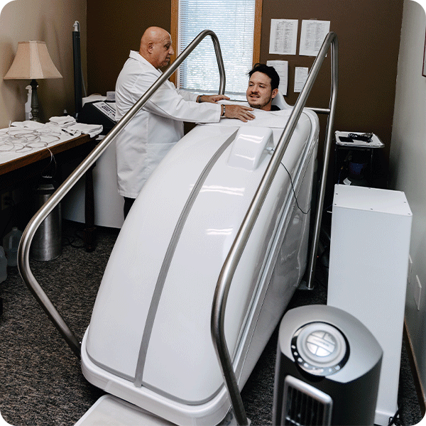 Doctor Tony monitors male patient sitting in the HOCATT Hyperthermia box