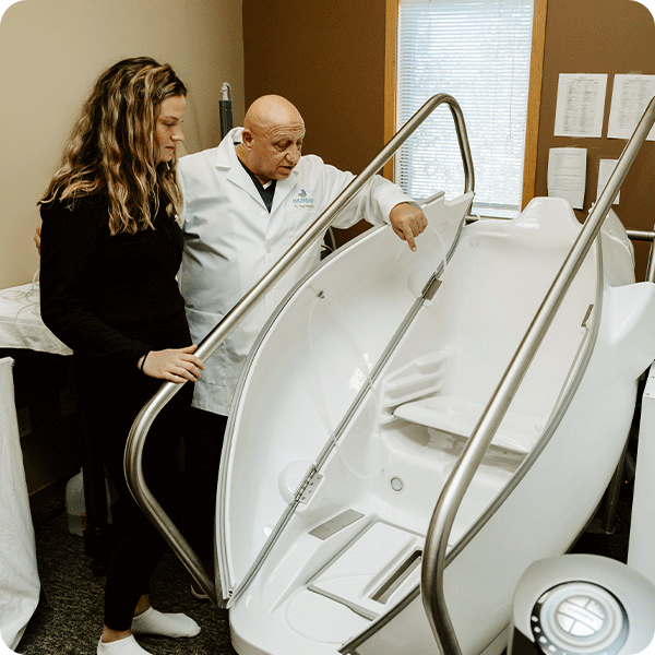 Doctor Tony instructs female patient on the HOCATT Hyperthermic Ozone chamber