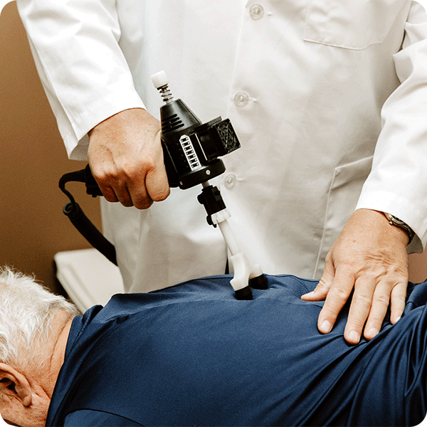 Close up of Doctor Tony using vibrating tool to relax male patient's spine