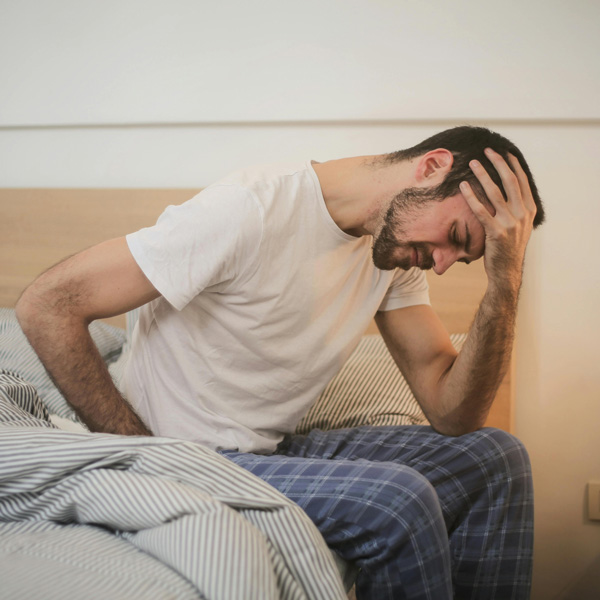 Man in pain, holding head and back, needing real solutions for his pain